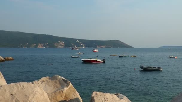 Herceg Novi モンテネグロ08 2022海の休暇旅行 アドリア海に浮かぶボート 地中海旅行事業 帆船と山 塩水に小さな波紋 天気は晴れ 石や岩 — ストック動画