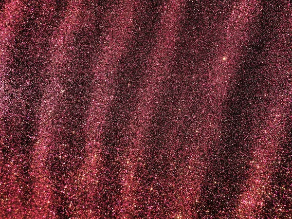 Bokeh light of pink glitters on black background. Magenta glitter texture. Sparkling glitter wrapping paper with sequins and sparkles. Festive purple bokeh and glitter. Diagonal stripes and waves.