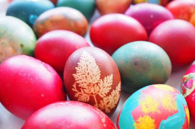 Paskalya sepeti, renkli yumurtalarla yakın plan. Kırmızı ve kahverengi kabuklu haşlanmış tavuk yumurtaları, geleneksel tariflere göre soğan kabuğuyla boyanmış. Bitki yaprakları kullanılarak yapılan çiçek deseni