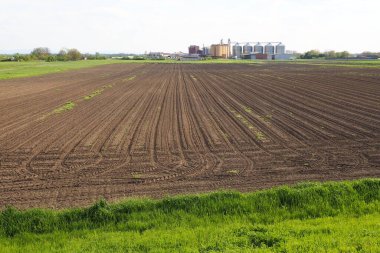 Macvanska Mitrovica, Sırbistan, 27 Nisan 2023. Pürüzlü tarla, traktörün geçişinden sonra soldaki izler. Tarım, nüfusa yiyecek sağlamak. Bahar tarım işi. Buğday asansörü