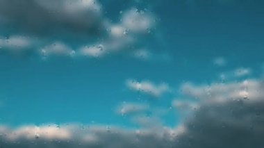 Kara bulutlar açık beyaz bulutlara ve mavi gökyüzüne yol verir. Camın üzerinde hızlı bir damla hareketi. Gökyüzü zaman atlaması. Sis ya da sis.