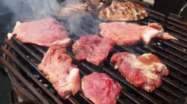 Izgarada ızgara ızgarada ızgara, alevler ve duman içinde ızgara etli domuz eti. Izgara sulu biftek piknik kutlaması için hazır. Kebap ve barbekü çatalı eti hareket ettirir.