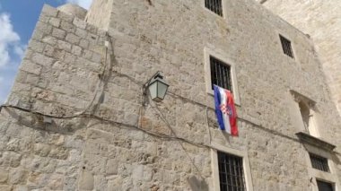 Dubrovnik, Hırvatistan, 08.14. 2022 gezi ve turizm. Hırvatistan 'ın ulusal bayrağı resmi devlet simgesi. Bayrak St. Dominic Caddesi 'ndeki bir pencereden asılmış. Antik taş manastır duvarları