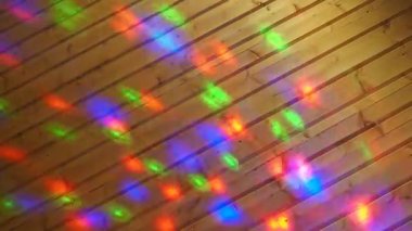 Christmas or New Year laser light show on a wooden wall indoors. Festive or disco lighting. Multi-colored light reflections of red, blue, green and purple run across the surface. Light projector