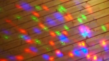 Christmas or New Year laser light show on a wooden wall indoors. Festive or disco lighting. Multi-colored light reflections of red, blue, green and purple run across the surface. Light projector