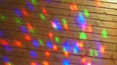 Christmas or New Year laser light show on a wooden wall indoors. Festive or disco lighting. Multi-colored light reflections of red, blue, green and purple run across the surface. Light projector