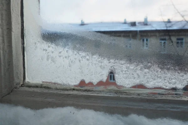 玻璃上有冰 雪和结冰的水晶体 双木制窗框窗 窗外是一条街和一座建筑物 能源效率和节能 冬天的冷经济危机 冰冻的城市 — 图库照片