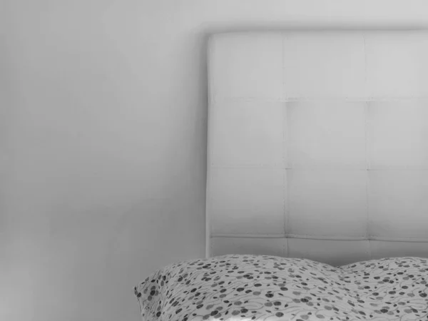 stock image Soft headboard. Upholstery for furniture made of genuine or artificial leather and quilted fabric. Soft headboard against a light wall. Black and white monochrome photo.