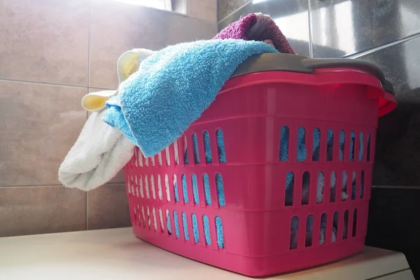 洗濯バスケットのタオル 青とピンクの綿のテリータオルはピンクのプラスチックバスケットに投げ込まれます ハウスキーピングだ 洗濯前に洗濯を保管 分離してください 窓から上からの光 — ストック写真
