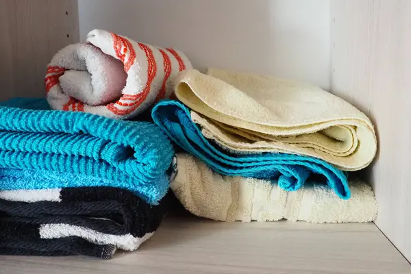 Stack of colorful clean towels on grey background. Ironing clothes on  ironing board. Stack of clean towels on table. Colored towels. Space for  text. Hygiene, fabric, laundry,spa and textile concept. Stock Photo