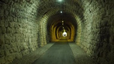 Karadağ, Herceg novi, Meljine, Zelenika, 13 Ağustos 2022. Eski bir demiryolu tüneli kayanın içindeki yaya geçidine dönüştü. İnsanlar yürüyor. Tünelin sonundaki bir ışık. Taş kaldırım