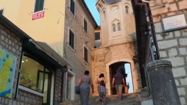 Herceg Novi, Karadağ, 08.10.2022 Sahat Kula saat kulesi, iki kare arasındaki bir geçit - Nikola Curkoviç ve Belavista. Bu popüler bir turistik ilgi odağı. Turistler merdivenlerden inip çıkıyorlar.