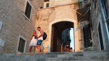 Herceg Novi, Karadağ, 08.10.2022 Sahat Kula saat kulesi, iki kare arasındaki bir geçit - Nikola Curkoviç ve Belavista. Bu popüler bir turistik ilgi odağı. Turistler merdivenlerden inip çıkıyorlar..