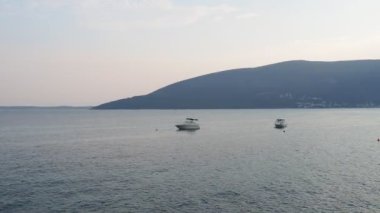 Herceg Novi, Karadağ, 08.10.2022 Rocky sahili. Denizde sakin ol, su dalgalanmaları. Dağ ufku. Gemiler demir aldı. Güzel bir yaz akşamı. Denize balık tutmaya. Adriyatik Akdeniz 'de Tatil.