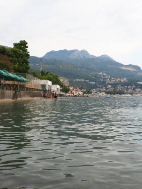 Herceg Novi Montenegro 08.09.2022 Deniz tatili Adriyatik gezisi Akdeniz seyahati. Rocky plage dağları. Sudaki dalgalar. İnsanlar yüzer, güneşlenir ve sahilde eğlenir. Sudaki kadın ve erkekler