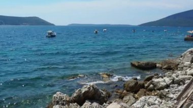 Herceg Novi, Karadağ 08.13.2022 Deniz Tatili. Adriyatik Denizi 'nde tekneler yüzer. Akdeniz seyahat işi. Yelkenliler ve dağlar. Su dalgalanmaları. Güneşli bir hava. Balık tutmak rahatlatır. Turkuaz dalgalar