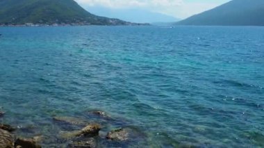 Herceg Novi, Karadağ. Deniz kıyısı tatili. Deniz gezileri. Adriyatik Denizi 'nde tekneler yüzer. Akdeniz seyahat işi. Dağlar. Suyun üzerinde küçük dalgalanmalar. Dalgalarda gökyüzü yansıması. Boka-Kotor lagune.