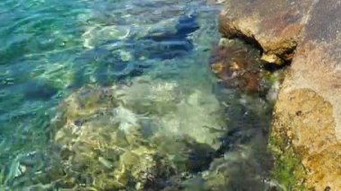 Yeşil mavi turkuaz şeffaf deniz tuzlu su dokusu. Su yüzeyinin üst görüntüsü ve dalgalanmalar. Su dalgaları arka planda. Dalgalar kayalık kıyıya çarpıyor, köpürüyor ve köpürüyor.