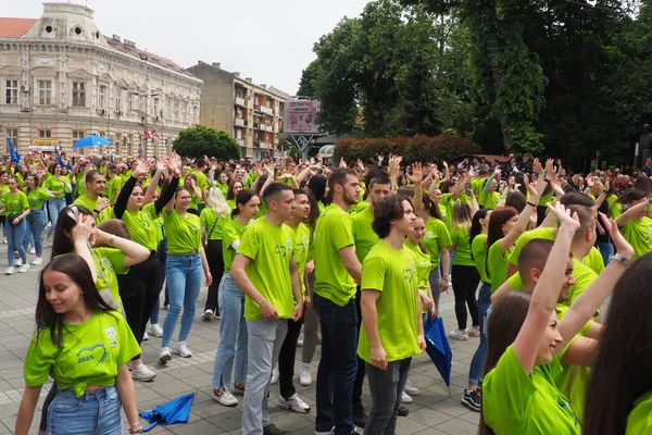 stock image Sremska Mitrovica, Serbia, May 19 2023 Ball of graduates of schools and technical schools on the central square. Youth performs a collective dance. Girls and boys wear green t-shirts. Prom degree day.