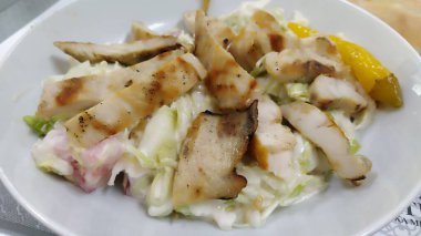 Sezar sebze salatası. Popüler bir Amerikan yemeği. Restoranda beyaz bir tabakta sebze salatası ve ızgara tavuk. Dilimlenmiş salatalık, domates, marul, mayonez ile karıştırılmış tavuk parçaları.