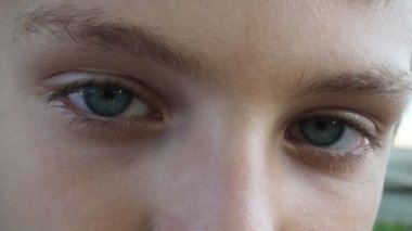 Erkek, beyaz, sarışın, 10 yaşında. Yüzü yakın çekim, gözlere odaklan. Gri-mavi gözlerle ciddi ve eğlenceli bir bakış. Sağlıklı bronzlaşmış deri. Çocuğun geri kalanı nehirde. Pozitif duygu