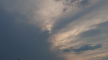 Cirrus bulutları güneş diskini bulutlarla kaplar. Güneşin yoğun kara bulutların ardında kayboluşu. Güneş ışınları sisli. Cadılar Bayramı için gün batımı. Hava tahmini. Gökyüzü arkaplanı