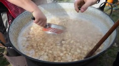 Sremska Mitrovica, Sırbistan 02.19.22 kalibrelik bir yağ fıçısının içinde yakacak odun. Pişmiş domuz derisi, yağda kızartılmış, kavrulmuş domuz kıtırı ya da çizik üretmek için. Kazanda erimiş domuz yağı.
