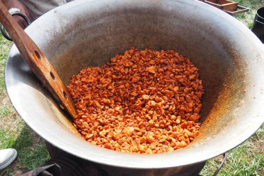 Yakacak odunların üzerinde büyük bir fıçıda yağ karıştırmak. Pişmiş domuz derisi, yağda kızartılmış, domuz kızartması veya çizik üretmek için kızartılmış. Kızarmış kahverengi çıtırtılar. Büyük dökme demir fıçı veya kazan