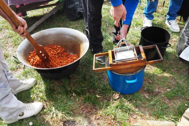 Sırbistan 'ın Sremska Mitrovica kenti, 02.19.2023 geleneksel bir şekilde domuz derisi pişirme kazan veya fıçısında. Yağlı kızartma. Çok fazla yağ sıkarsın. Metal pres makinesiyle sarsılıyor. Domuz eti çatırtısı ya da çizikler.