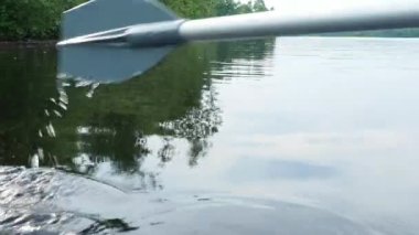 Kürek, kürek şeklinde küçük tekneleri hareket ettirmek için kürek şeklinde özel bir itme kuvveti. Lososinnoye Gölü 'nde balık tutuyorum, Karelia. Kıyıda sedge. Sahilden ayrılıyoruz.