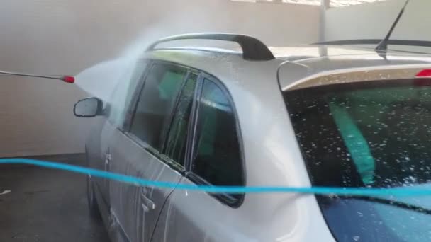 塞尔维亚斯雷姆斯卡米特罗维察 8月29日20时23分 一名男子在洗车过程中清洗一辆灰色汽车 在高压下从软管中将水和泡沫倒入机器体内 玻璃和金属表面变得干净 — 图库视频影像
