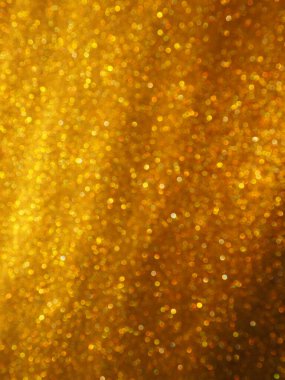 Altın parıltılarının Bokeh ışığı. Altın parıltı dokusu arka planı. Pullu ve pırıltılı, ışıltılı ambalaj kağıdı. Şenlikli altın bokeh ve parıltı. Çapraz çizgiler ve dalgalar.