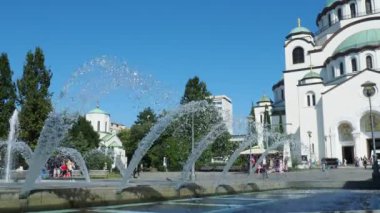 Belgrad, Sırbistan, 9 Eylül 2023 St. Sava Kilisesi, bir Sırp Ortodoks Tapınağı. Muhteşem çan kuleleri. Çeşmeye su sıçrıyor. Turistler ve inançlı insanlar tapınağın önünde yürürler.