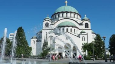Belgrad, Sırbistan, 9 Eylül 2023 St. Sava Kilisesi, bir Sırp Ortodoks Tapınağı. Muhteşem çan kuleleri. Çeşmeye su sıçrıyor. Turistler ve inançlı insanlar tapınağın önünde yürürler.