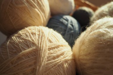 White, beige and blue woolen and acrylic threads wound into a ball or skein. Several skeins of light yarn in a basket. Knitting as a hobby. A clew of thread clipart