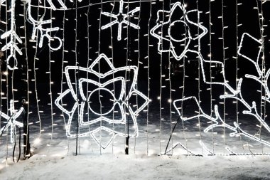 New Year Christmas illumination of city streets. Flashing, flickering, shining, gleaming of electric bulbs and lights. Beautiful garlands and architectural forms. LED energy-saving garlands. Snowflake