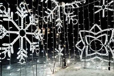 New Year Christmas illumination of city streets. Flashing, flickering, shining, gleaming of electric bulbs and lights. Beautiful garlands and architectural forms. LED energy-saving garlands. Snowflake