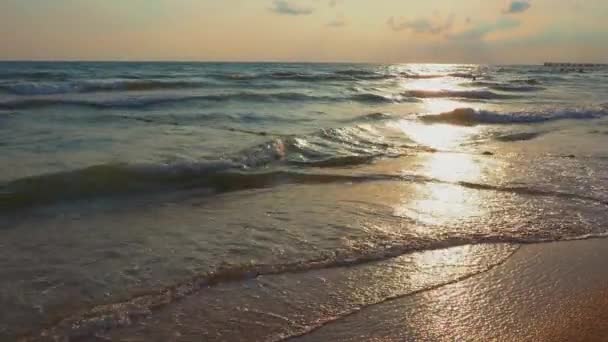 穏やかな波が砂浜を転がします 海や海での日没 水の動きだ 波は泡で荒れ狂う 観光地だ 旅行ビーチのテーマ 波の中の太陽の反射 — ストック動画