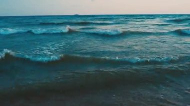 Sakin dalgalar kumlu sahilde yuvarlanıyor. Denizde ya da okyanusta gün batımı. Su hareketi. Dalgalar köpükten köpürüyor. Turist cenneti. Kum, deniz suyu sütundan görülebilir. Karadeniz.