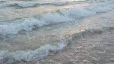 Karadeniz 'in kumlu kıyısı. Sakin dalgalar kumlu sahilde yuvarlanıyor. Denizde ya da okyanusta gün batımı ve artçı ışıltı. Su hareketi. Dalgalar köpükten köpürüyor. Turist cenneti. Güzel akşam deniz manzarası.