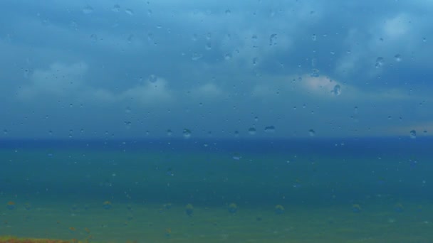 海の景色を望むガラス窓 深海に 地平線上の劇的な雷雲 嵐の警告 レインドロップドリッピングクローズアップ 窓から水が流れ出る 天気予報 距離の重い雲 — ストック動画