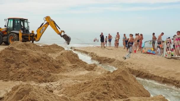 アナパ ロシア ヴィタヤゼヴォ公共ビーチ 掘削機はバケツを使用して砂にトレンチを掘り 大雨の後に砂丘の後ろに蓄積された下水を解放し 黒海に洪水を起こします クロウド — ストック動画