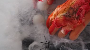 Derisi soyulmuş kanlı canavarlar ağlarına bir kaç insan gözü yerleştirir, düzenler ve saklar. Cadılar Bayramı ve korku. Ellerinden ve parmaklarından deri parçaları sarkıyor. Yaşlı cadı.