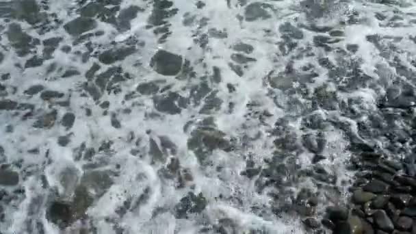 きれいな海の泡が付いている小石のビーチそして海の波 ブラックシー海岸の海岸 コーカサス山脈の湿った小石の海岸で海岸線の波 スココビーチには誰もいない海の景色 夏休みについて — ストック動画