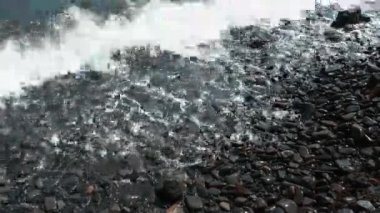 Çakıl taşı plajı ve temiz deniz köpüğüyle deniz dalgaları. Karadeniz kıyısının deniz manzarası. Kafkasya dağlarının ıslak çakıl taşlı sahillerinde kıyı dalgaları. Sukko sahilinde deniz manzaralı bir yer yok. Yaz tatili.