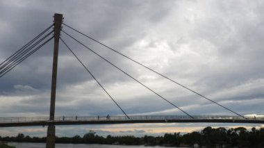 Sremska Mitrovica Sırbistan 10.28.23 Sremska Mitrovica ve Sava Nehri. St. Irineja 'dan Macvanska Mitrovica' ya yaya köprüsü. İnsanlar nehrin üzerindeki asma köprü boyunca yürüyüp bisiklete biniyorlar.