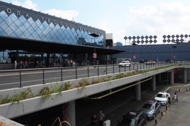 Belgrad, Sırbistan 09.17.2023 Nikola Tesla Uluslararası Surcin Havaalanı. Yeni havaalanı binaları. Uçakla uçan yolcu trafiğini arttır. Arabalar, insanlar, otobüs durağı, park yeri. Cam havaalanı duvarları.