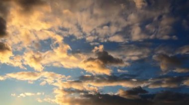 Atmosfer. Gün batımında ya da gün doğumunda hava durumu. Sarı bulutlar zaman ayarlı. Güzel bir akşam ve mavi gökyüzü. Ses ötesi ışık efekti. Kümülüs bulutları. İklim tahmini. Bulutlar gökyüzünde hızla akıyor.