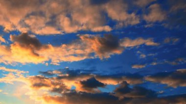 Atmosfer. Gün batımında ya da gün doğumunda hava durumu. Sarı bulutlar ağır çekimde. Güzel bir akşam ve mavi gökyüzü. Ses ötesi ışık efekti. Kümülüs bulutları. İklim tahmini. Bulut hızla gökyüzünde koşuyor