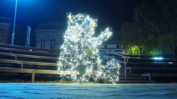 小さな建築形態のクマは 金属構造とガーランドで作られた上げられた足を持ちます 光の球根はテディベアかプーのウィニーの形で光ります 通りと広場のクリスマスの夜の装飾 — ストック動画